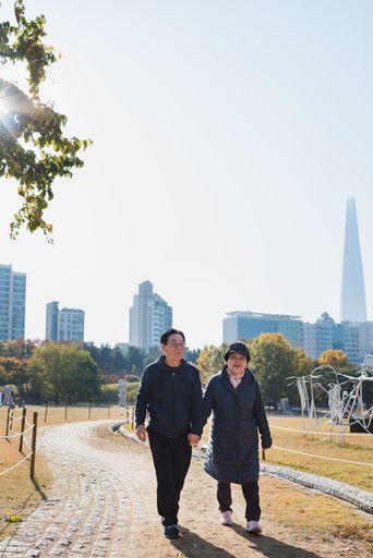 A Korean elderly couple holding hands and walking around a park in autumn in South Korea