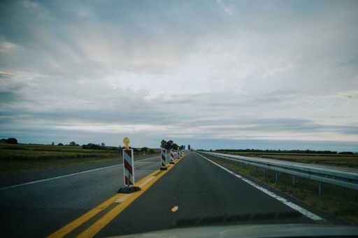 A view of a long road with sheet metal protective fence and yellow line