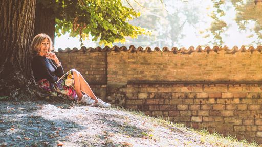 A beautiful elderly Caucasian woman sitting under a tree in daytime