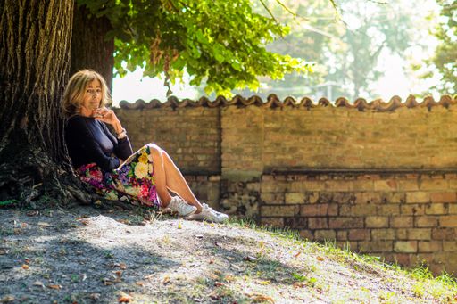 A beautiful elderly Caucasian woman sitting under a tree in daytime