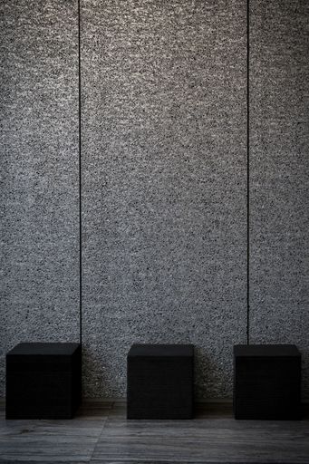 The three black cubes placed against a plain gray wall