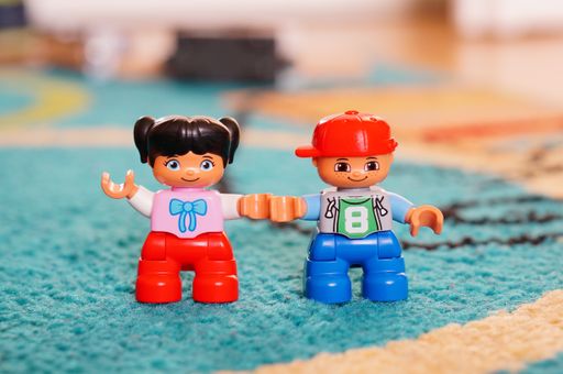 A closeup shot of Lego Duplo boy and girl figurines on a carpet floor
