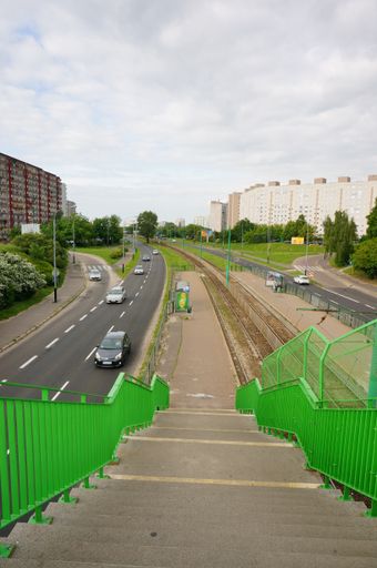 A vertical shot of green stairs leading down to a public transport tram stop on the Zegrze street