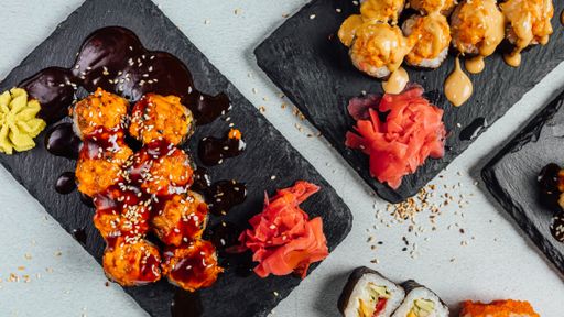 A top view of several plates of colorful sushi rolls arranged like circle and served with sauces