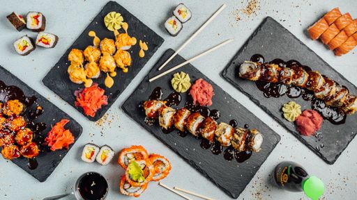 A top view of several plates of colorful sushi rolls arranged like circle and served with sauces