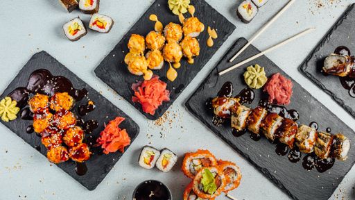 A top view of several plates of colorful sushi rolls arranged like circle and served with sauces