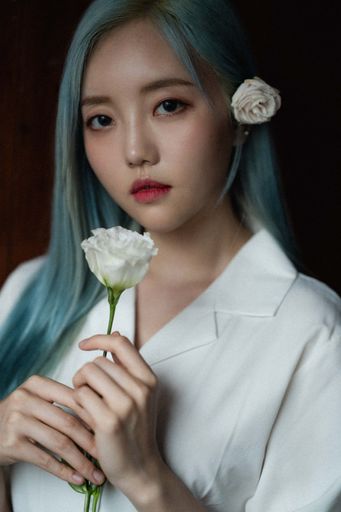 A portrait of a South Korean woman with light blue hair holding a white rose