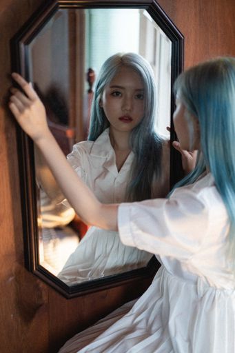 An attractive blue-haired South Korean female posing near the mirror