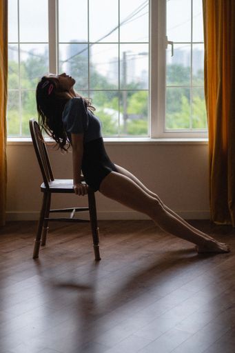 A vertical shot of a sexy South Korean female leaning on a wooden chair