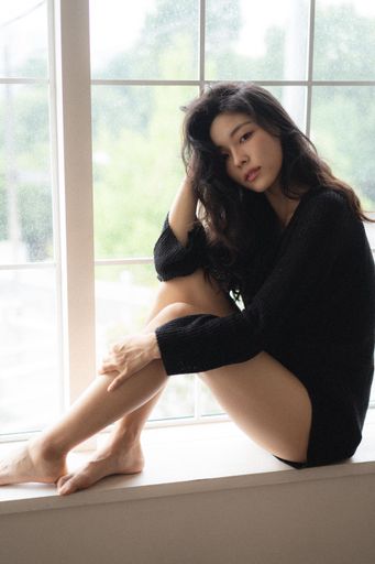 A beautiful South Korean female sitting on windowsill