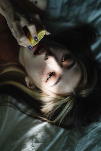 An attractive South Korean female with lemon in her hand lying on the bed