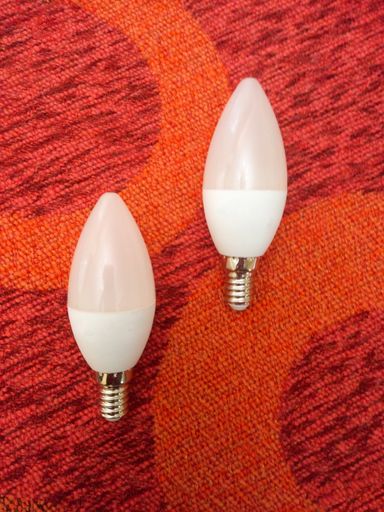 closeup shot of a modern eco white led electric candelabra or chandelier light bulb on a red background