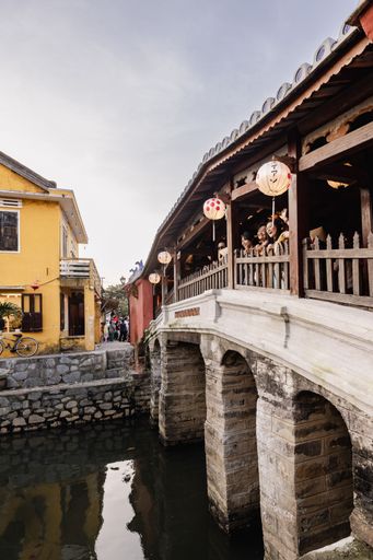 Japanese Covered Bridge in Hoi An, Vietnam, with lanterns and tourists enjoying the view, reflecting cultural heritage and architecture.
