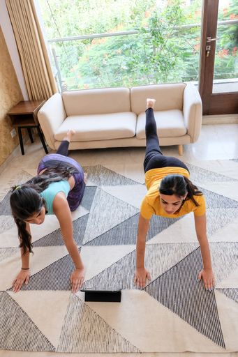 A vertical shot of two young females doing yoga exercises indoors on the floor