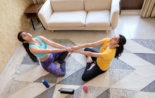A closeup of two girls practicing yoga at home.