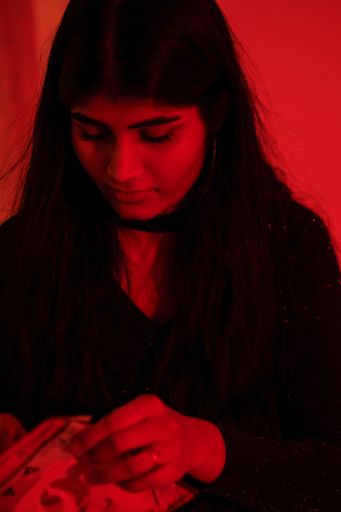 A vertical closeup of a girl in a black dress in red background.