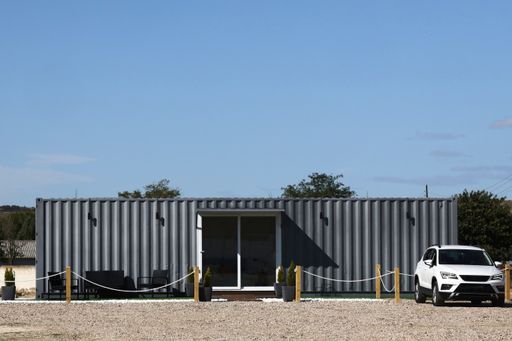 An exterior view of a building in a wilderness with a car in front of it
