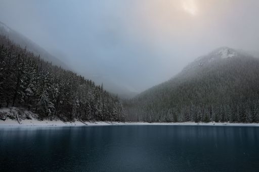 The sun peeking through winter clouds over a lake in the Cascade Mountains, Washington