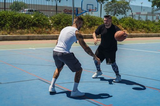 The two young males playing basketball on the outdoor court