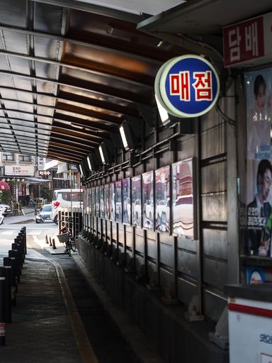 A scenic shot of a cigarette shop on the corner of the road in South Korea with a blue and red sign
