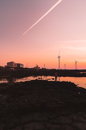 A man standing on cracked soil with windmills background in South Korea during sunset