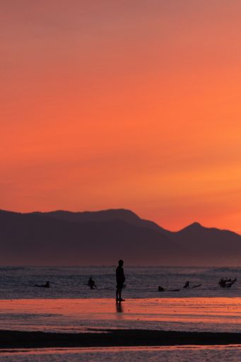 A silhouette shot of people enjoying the sea against breathtaking sunset in South Korea