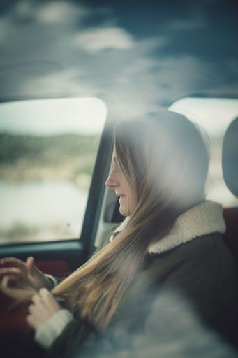 A Caucasian woman from Italy in the car playing with her hair