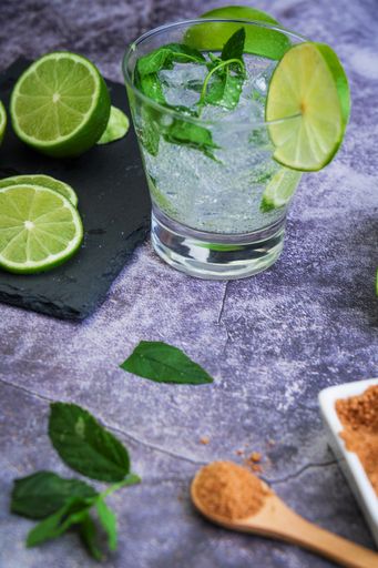 A process of preparing a refreshing drink with lime slices, mint and ice