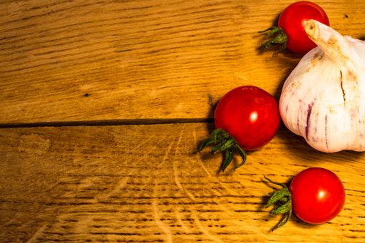 A closeup shot of garlic bulb and tomatoes on a wooden table