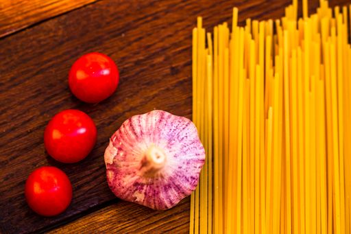 A closeup of the fresh cherry tomatoes with garlic and pasta.