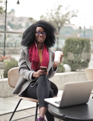 A vertical shot of a young black female working with her laptop in a cafe
