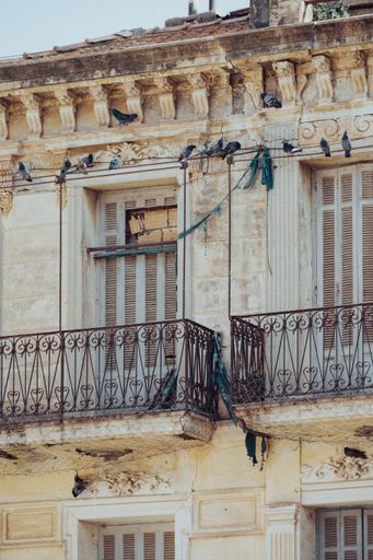 A vertical shot of the facade of an old damaged building with balconies in Bejaia, Algeria