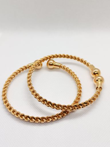 A closeup of beautiful gold bangles on a white background