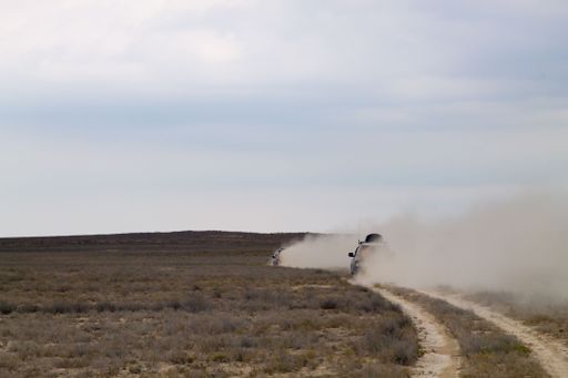 A thrilling scene featuring off road vehicles driving fast in desert landscape, creating dust clouds in Mangystau region, Kazakhstan, Central Asia
