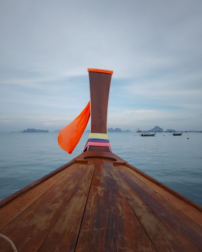 A traditional long-tail boat with colorful ribbons on a calm sea. Krabi, Thailand