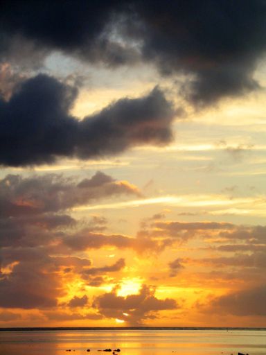 A vertical shot of a sea with the sun shining behind the clouds in Tahiti. Bora  Bora