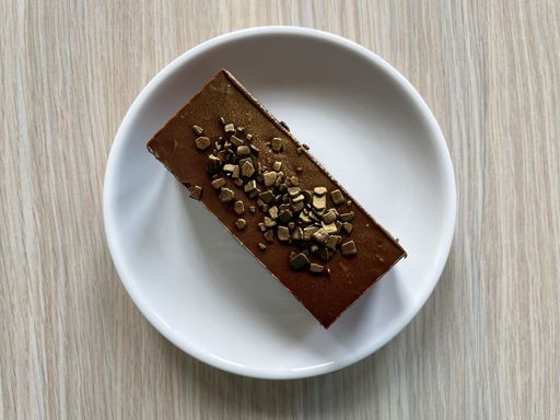 A top view of a chocolate cake decorated with gold sprinkles served on a white plate on a wooden table