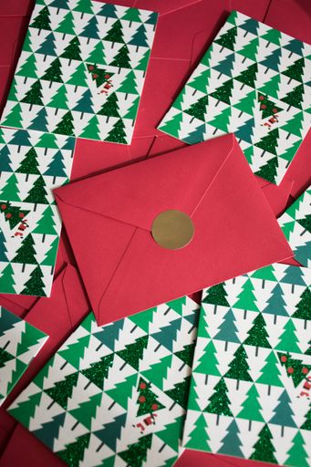 Festive Christmas cards with green tree patterns and red envelopes, perfect for holiday greetings.