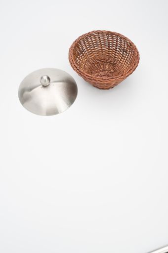 A top view of a round wicker basket next to a metal cover isolated on a white background with free space