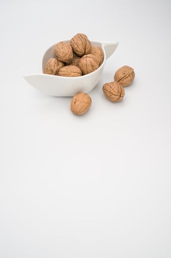 A close up of a white bowl with Stack Walnuts isolated on a white background with free space
