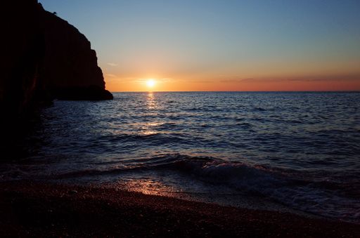 A beautiful view of the sunset over the calm waves of the ocean near the cliff