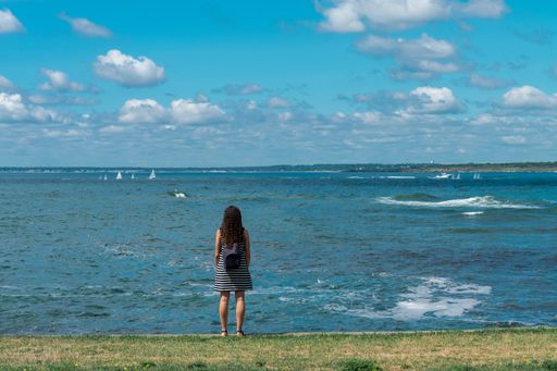 A curly girl with backpack enjoying the seascape