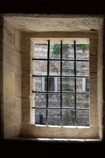 a vertical shot of antique window with metal grill from the inside