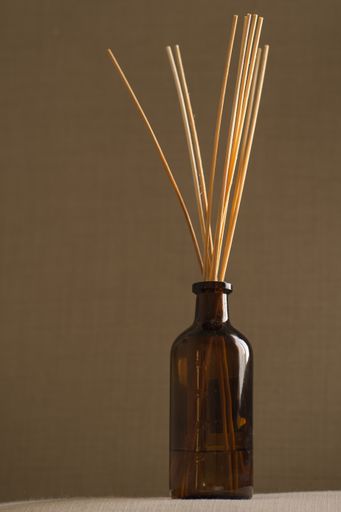 A closeup of aromatic sticks in a glass jar on a brown background