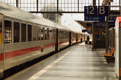 An Intercity train is ready to depart from the platform at Frankfurt am Main Central Station. Sunny backlight with shadows and reflections.