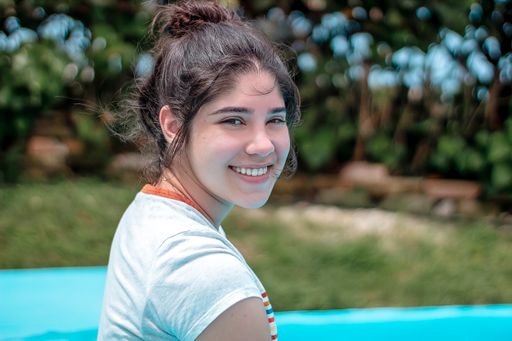 A closeup shot of a beautiful Hispanic girl sitting near the swimming pool in Cuba
