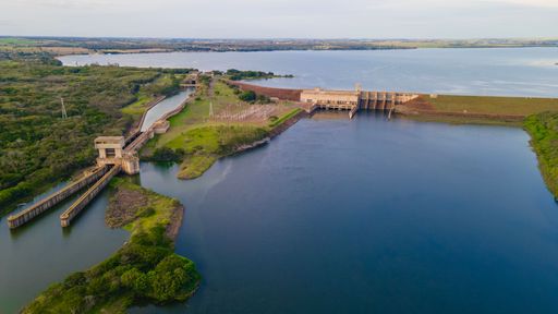 Aerial view of a hydroelectric dam surrounded by lush greenery and a vast lake, showcasing renewable energy infrastructure.