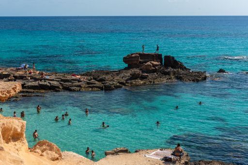 A high angle shot of people in the Formentera beach of Calo des Mort in the Balearic Islands, Spain