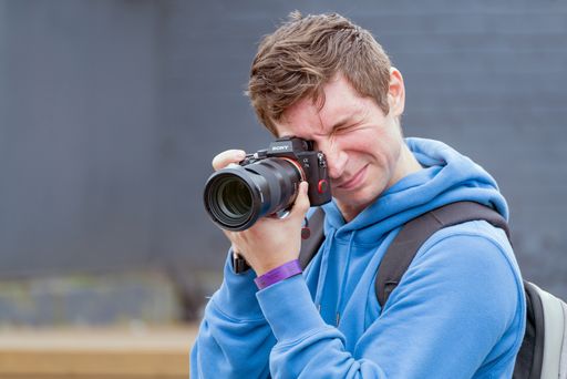 A shallow focus of a young male photographer taking pictures with his camera