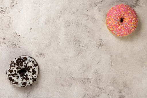 A top view of delicious strawberry glazed doughnut with sprinkles and cookies and cream doughnut with space for text